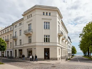Spokojna ulica mieszkaniowa na Witominie w Gdyni z kolorowymi blokami, zielenią i zalesionym wzgórzem w tle.